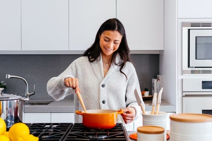 Home cook stirring a pot in a bright kitchen